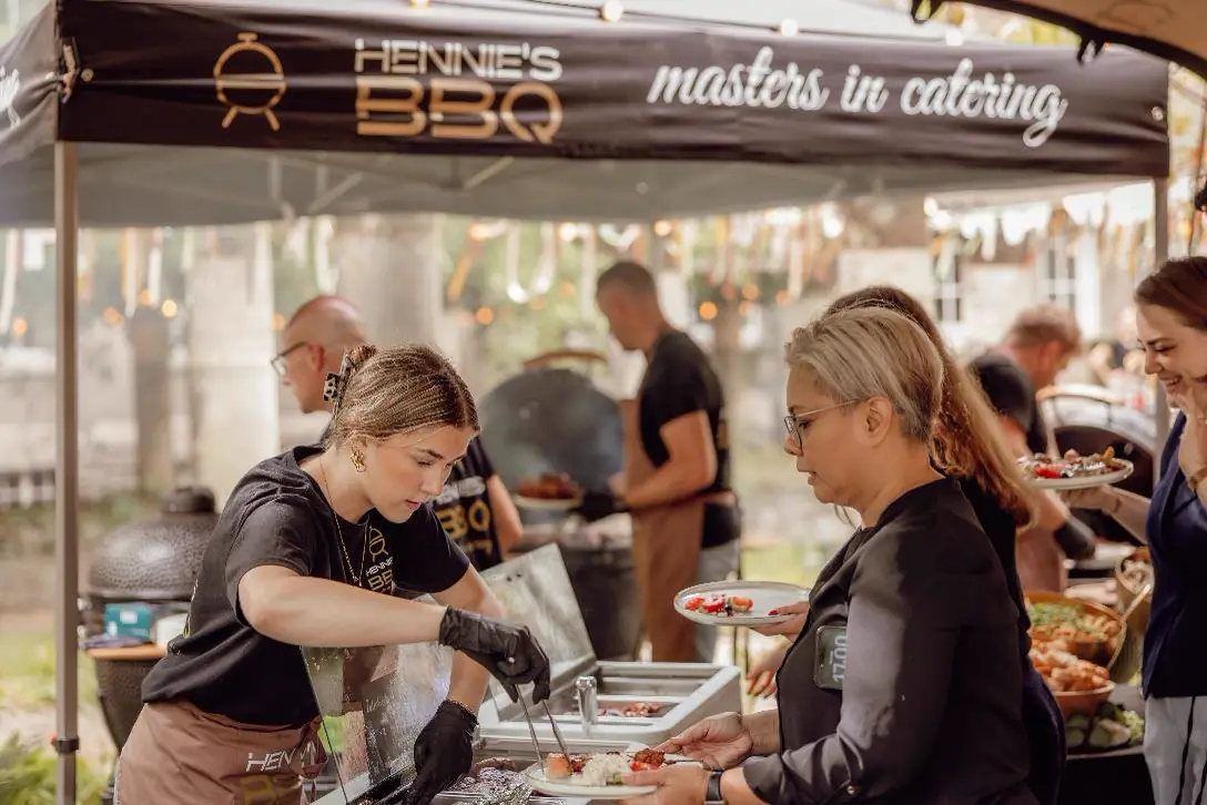 Bediening van Hennie's BBQ schept op aan het buffet onder de tent