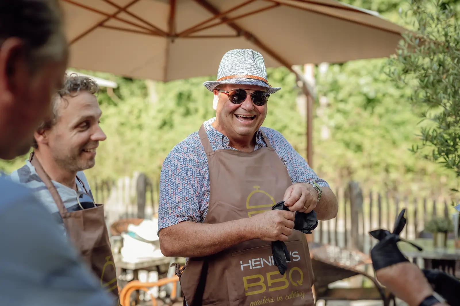Een lachende deelnemer met hoed en schort van Hennie's BBQ